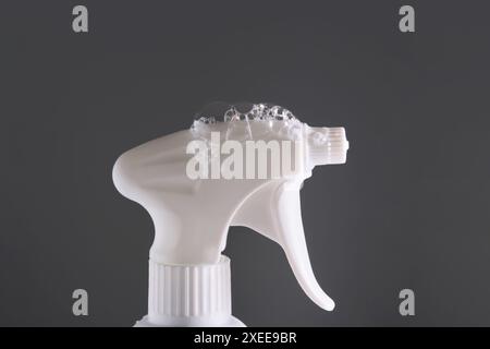 Cleaning product with a sprayer on a dark background owith soap bubbles. Stock Photo