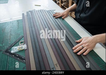 A tanner makes leather belts in a workshop. Close-up of a man's hands. Stock Photo