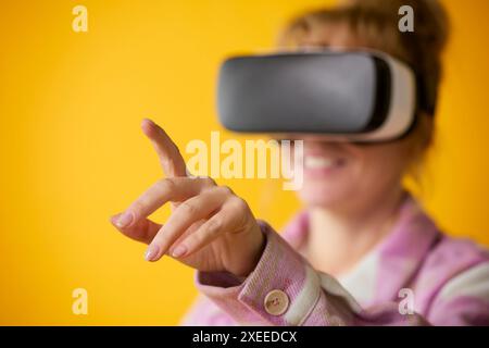 Woman Exploring Wearing Virtual Reality Headset Against Yellow Studio Background Stock Photo
