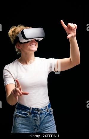 Woman Exploring Wearing Virtual Reality Headset Against Black Studio Background Stock Photo