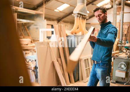 Carpenter Working In Woodwork Workshop Choosing Wood For Project Stock Photo