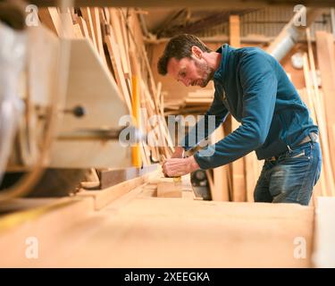 Carpenter Working In Woodwork Workshop Measuring Wood For Project Stock Photo