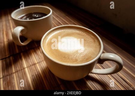 Two cups of coffee, Americano and cappuccino, in a cafe, an atmospheric photo Stock Photo