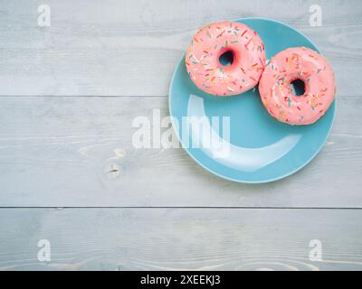 Pink donuts on gray wooden background, copy space, top view Stock Photo