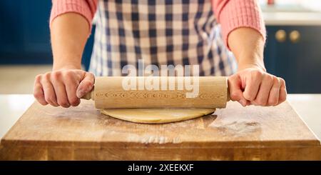 Close Up Of Woman At Home In Kitchen Rolling Out Dough With Rolling Pin On Worktop Or Counter Stock Photo