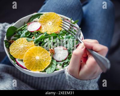 Woman in jeans at bed, holding vegan salad bowl Stock Photo