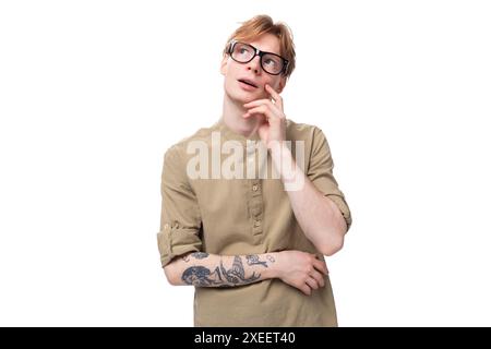 Young inspired european male student with red golden hair dressed in light brown shirt dreaming looking up Stock Photo