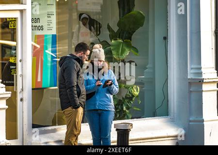 Street conversation. A young woman shows something on her phone to the man. Dublin. Ireland. Stock Photo
