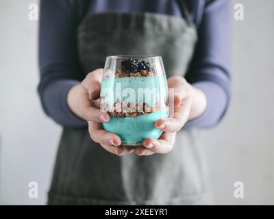 Spirulina smoothie and granola in woman hands Stock Photo