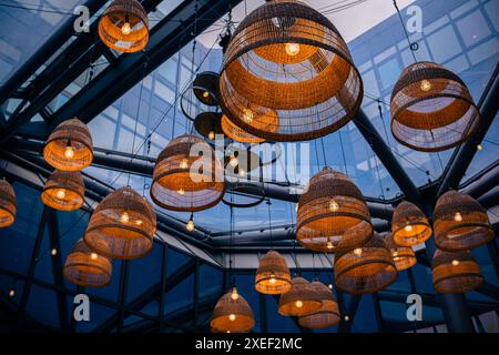 Lamps with wicker shades under a glass ceiling in modern business centre or restaurant. Stock Photo