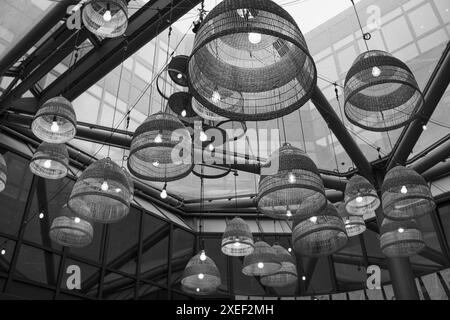 Lamps with wicker shades under a glass ceiling in modern business centre or restaurant. Stock Photo