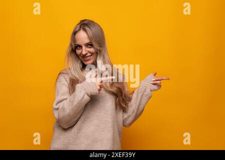 Young woman pointing with her hands at the wall over isolated background Stock Photo