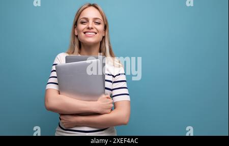 Smart successful confident girl student with a laptop in her hands on a blue isolated background Stock Photo
