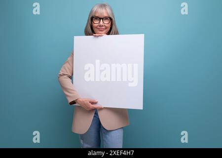 Close-up of a confident mature woman in a jacket with a mocap abstract poster on a bright background with copy space Stock Photo