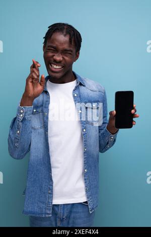 Smiling african man with black dreadlocks using smartphone Stock Photo