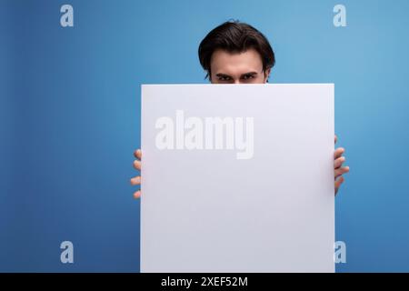 Young brutal brunette guy with poster mockup Stock Photo