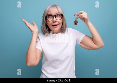 Turnkey property. mature woman pensioner holding apartment keychain on studio background Stock Photo