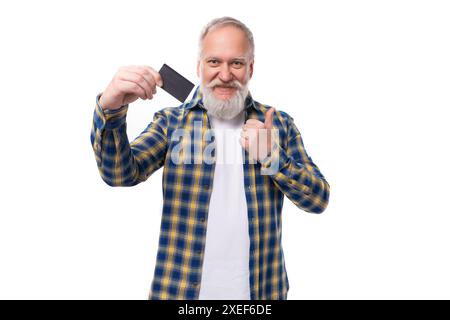 Mature gray-haired man with a beard in a shirt keeps pension money on a card on a white background with copy space Stock Photo