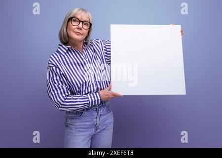 60s middle aged business woman showing blank billboard with mockup on bright studio background Stock Photo