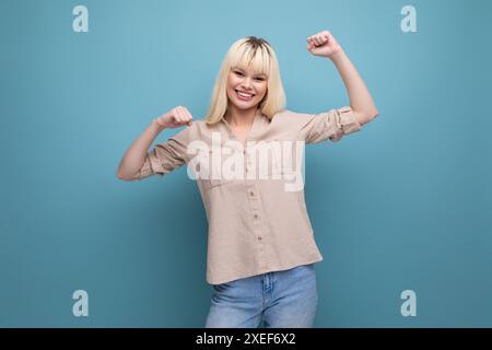 Portrait of joyful charismatic successful blonde young lady on background with copyspace Stock Photo