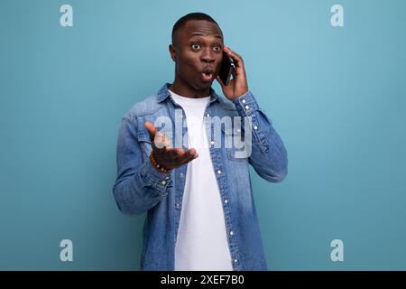 Surprised young american man in denim clothes talking on the phone Stock Photo