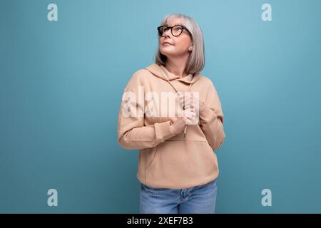 Portrait of a dreamy mature woman with gray hair in a casual look on a studio background with copy space Stock Photo
