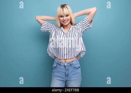 Positive energetic blond young lady in casual outfit with smartphone in studio Stock Photo