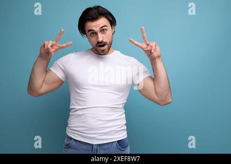 Confident young brunette guy in a white t-shirt and jeans Stock Photo