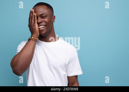 Handsome dark-skinned young american guy in a white t-shirt on the background with copy space Stock Photo
