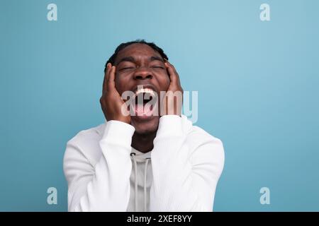 Happy surprised american 20s man with dreadlocks on background with copy space Stock Photo