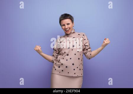Joyful emotional young caucasian dark-haired lady in a skirt and blouse with a short haircut Stock Photo