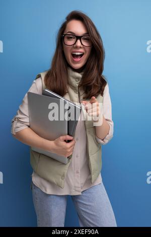 Positive 30s lady student holding documents and laptop on empty space background Stock Photo