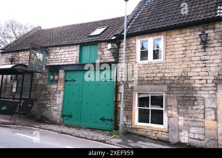Village Bradford on Avon garage painted green old style stone cottage house built building historic blocked up doorway lights barn hinges windows path Stock Photo