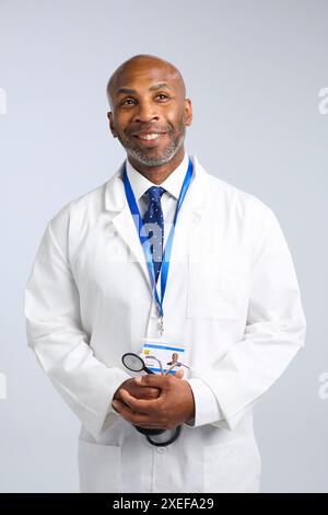 Studio Portrait Of Mature Doctor Wearing White Coat With Stethoscope And Lanyard Stock Photo