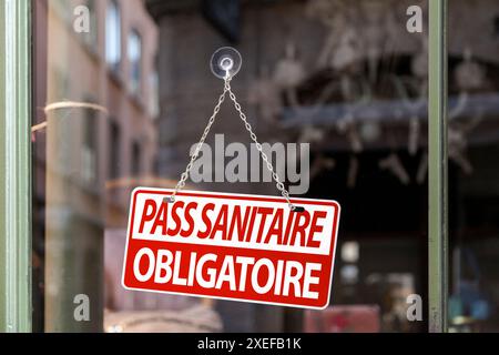 Close-up on a red and white sign in a window with written in French "Pass sanitaire obligatoire", meaning in English "Compulsory health pass". Stock Photo