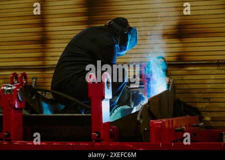 Unrecognizable man in workwear and protective helmet welding metal parts at work in factory, copy space Stock Photo