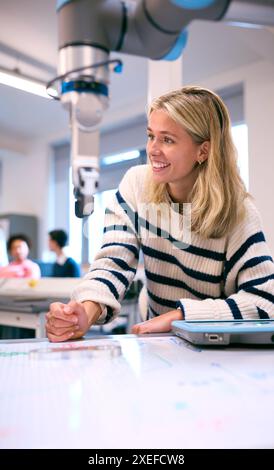 Female College Or University Engineering Student In Robotics Class Working On Robotic Arm Stock Photo