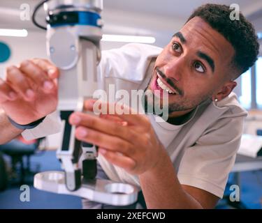 Male College Or University Engineering Student In Robotics Class Working On Robot Arm Stock Photo