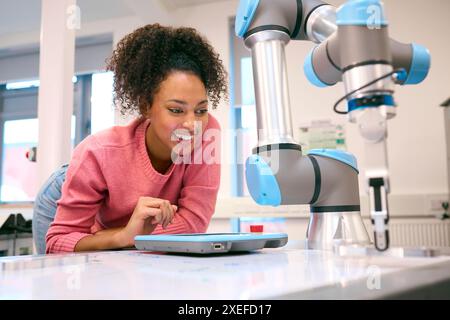 Female College Or University Engineering Student In Robotics Class Working On Robotic Arm Stock Photo