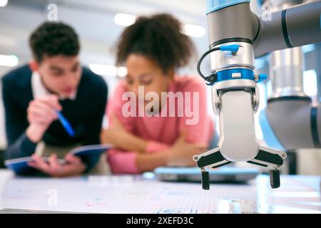 Male And Female College Or University Engineering Students In Robotics Class Working On Robot Arm Stock Photo