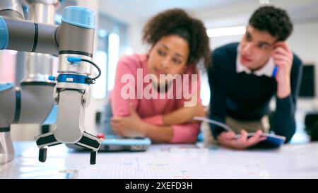 Male And Female College Or University Engineering Students In Robotics Class Working On Robot Arm Stock Photo