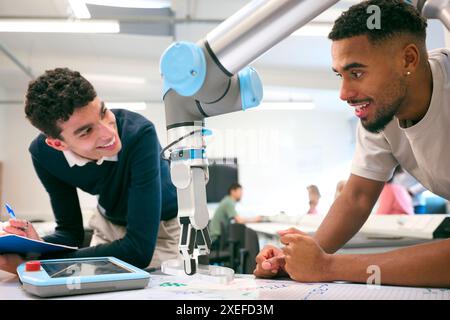 Two Male College Or University Engineering Students In Robotics Class Working On Robot Arm Stock Photo
