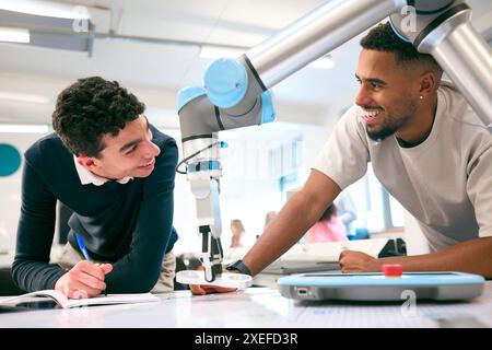 Two Male College Or University Engineering Students In Robotics Class Working On Robot Arm Stock Photo