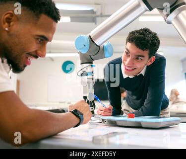 Two Male College Or University Engineering Students In Robotics Class Working On Robot Arm Stock Photo