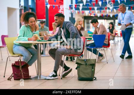 College Or University Students With Mobile Phone Working Together With Male Teacher In Study Area Stock Photo