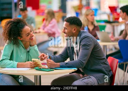 Two College Or University Students With Mobile Phone Working Together In Study Area Stock Photo
