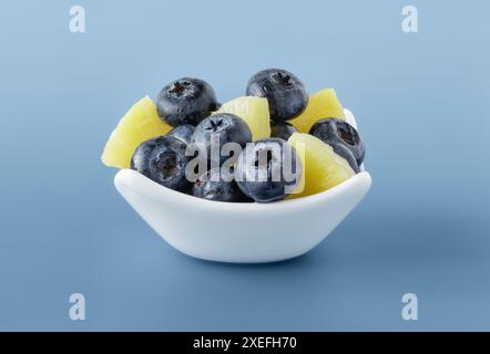 White bowl with fresh blue berries and pieces of pineapple Stock Photo