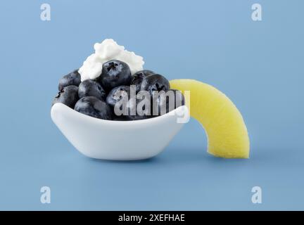 Fresh blue berries topped with cottage cheese and a slice of pineapple in white dish Stock Photo