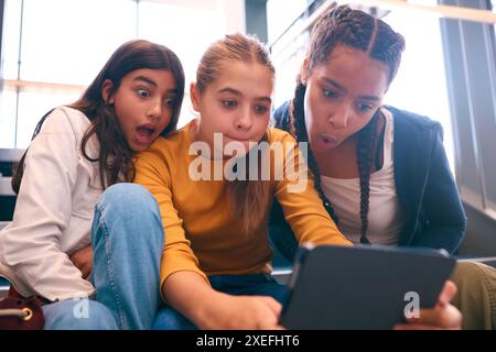 Three Female Secondary Or High School Pupils Inside School Building On Stairs With Digital Tablet Stock Photo