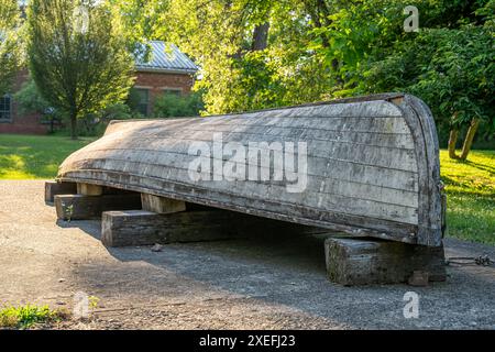 Old, weathered, gray wooden row boat upside down, inverted, on blocks. Stock Photo